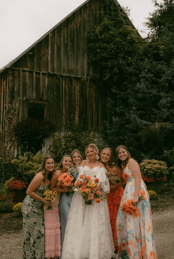 Barn And Blossom Nursery-PNW Weddings-Spokane-Bridesmaids In Floral Dresses In Front Of Historic Barn In Spokan
